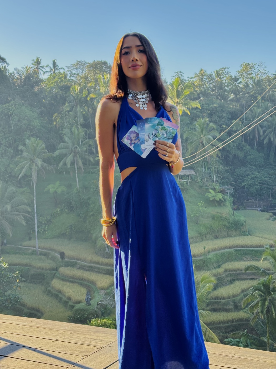 MAÏA holding tarot cards above the Ubud rice terraces